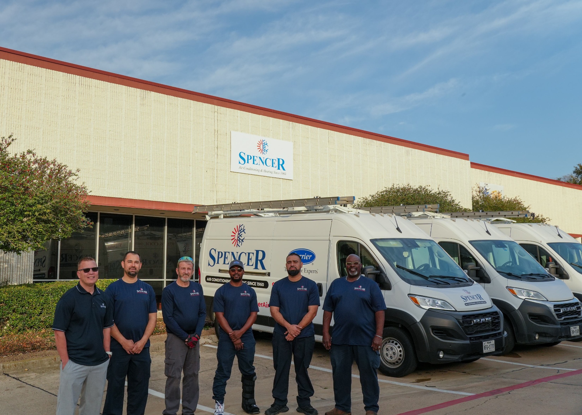 Spencer service technicians standing in front of the Carrier-equipped service fleet